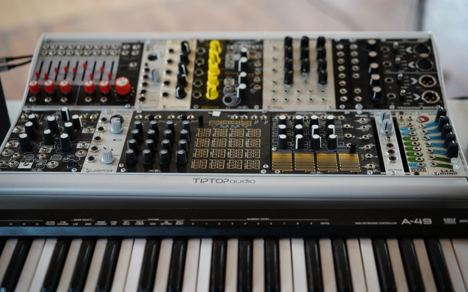 A fully populated Eurorack synth case with patch cables, hands adjusting a module