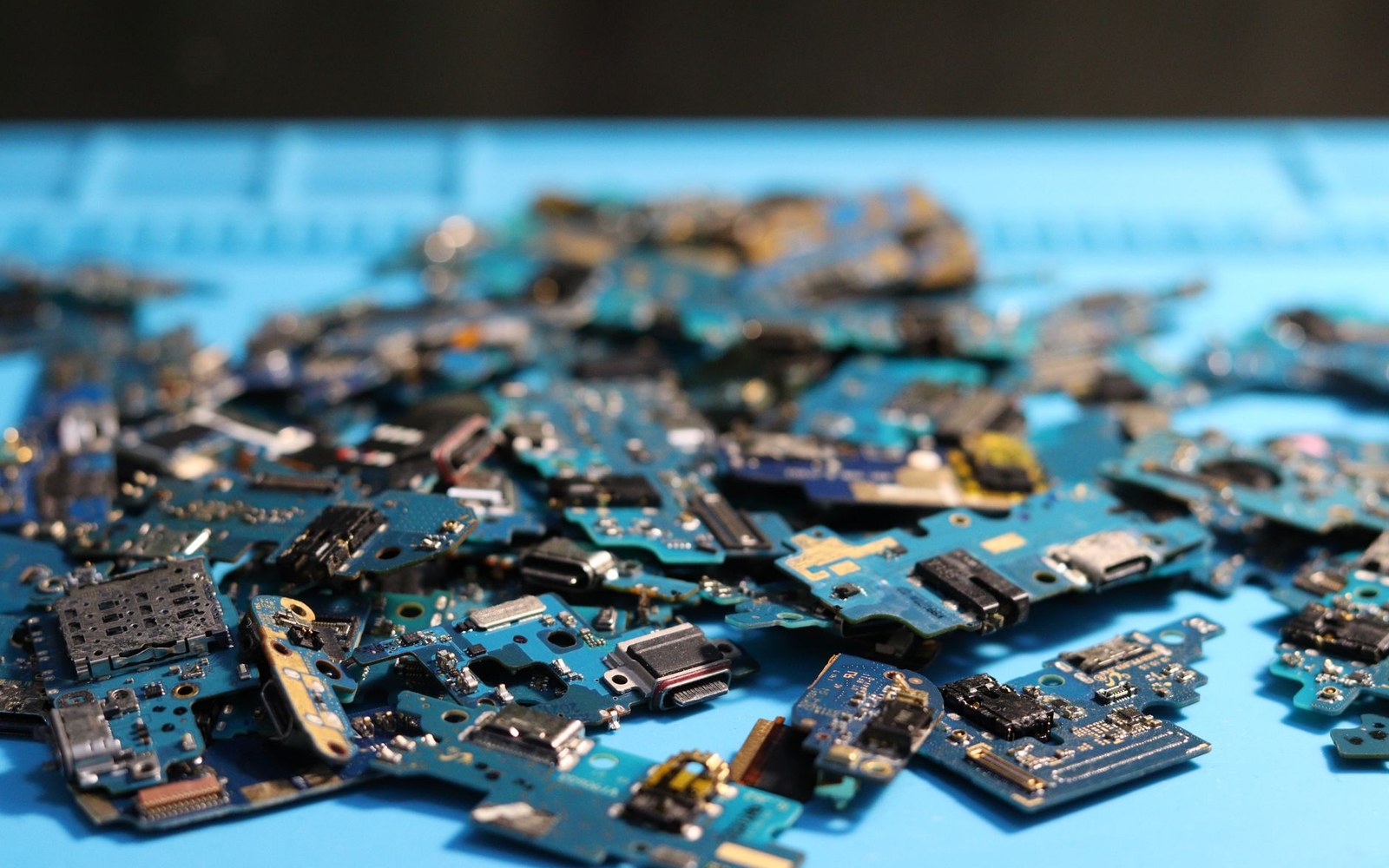 Pile of dismantled circuit boards and electronic components on a blue surface