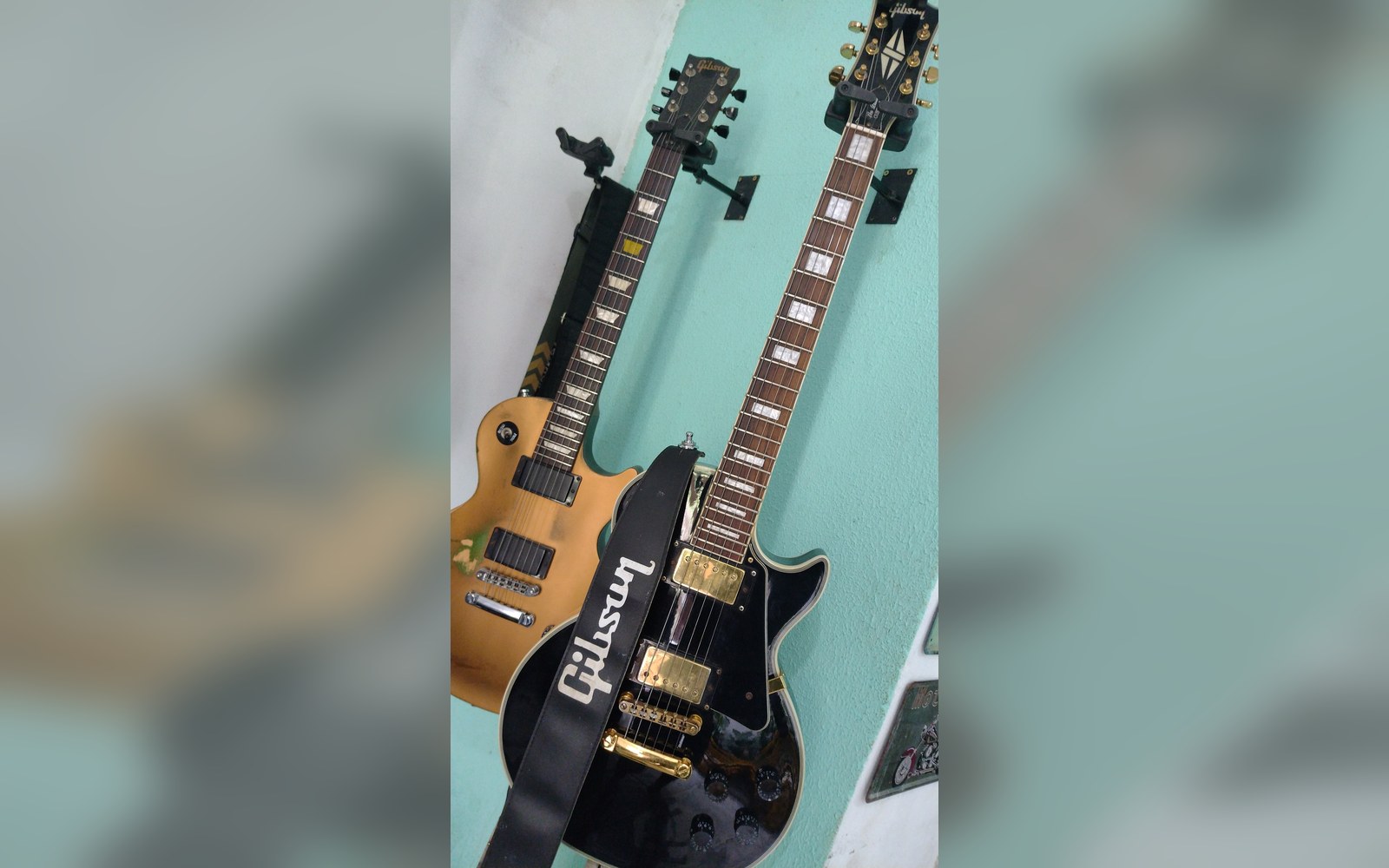 Two Gibson Les Paul guitars, one black and one gold top, mounted on a wall