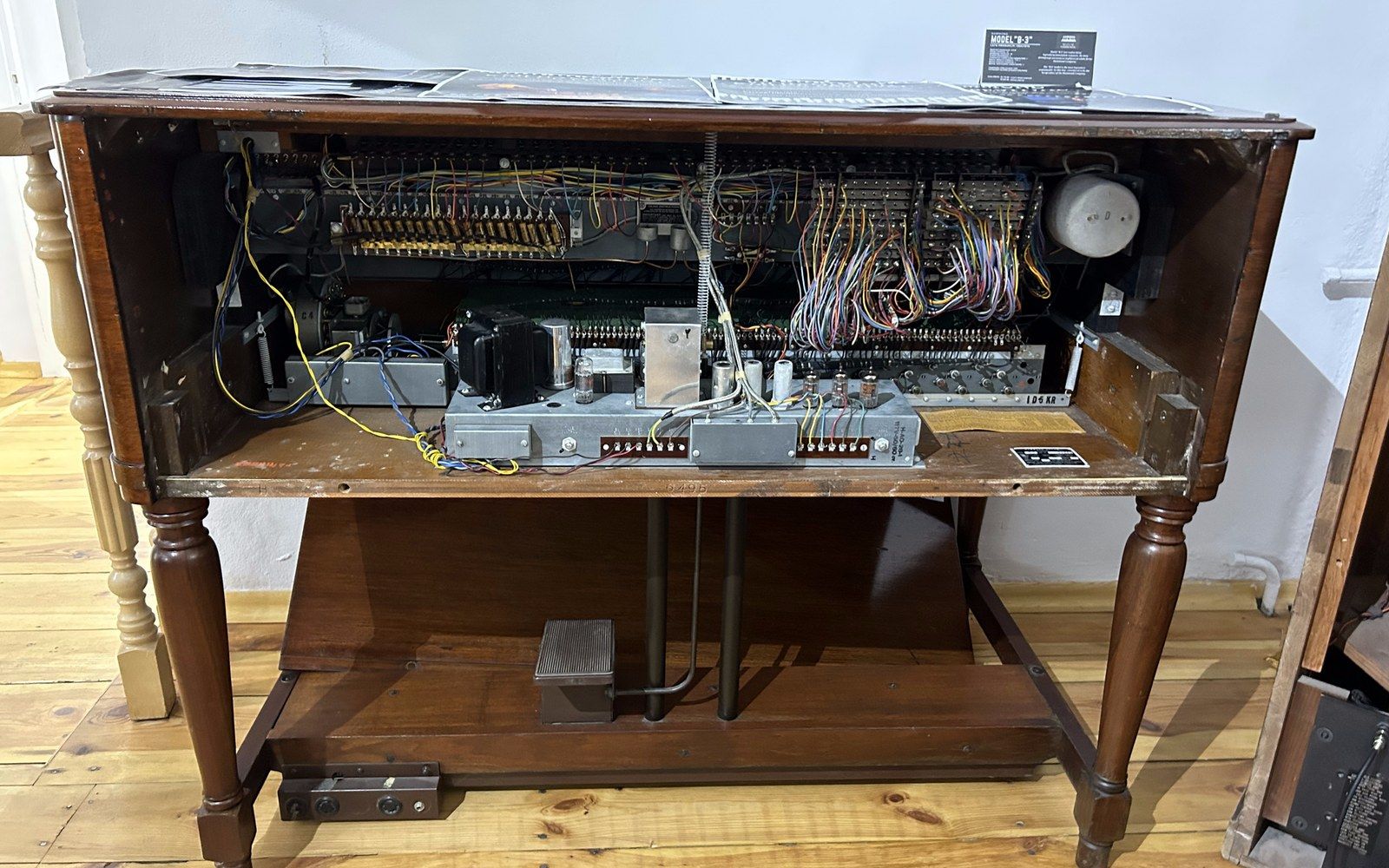 Wooden organ cabinet opened to reveal internal wiring, tube components and circuit boards