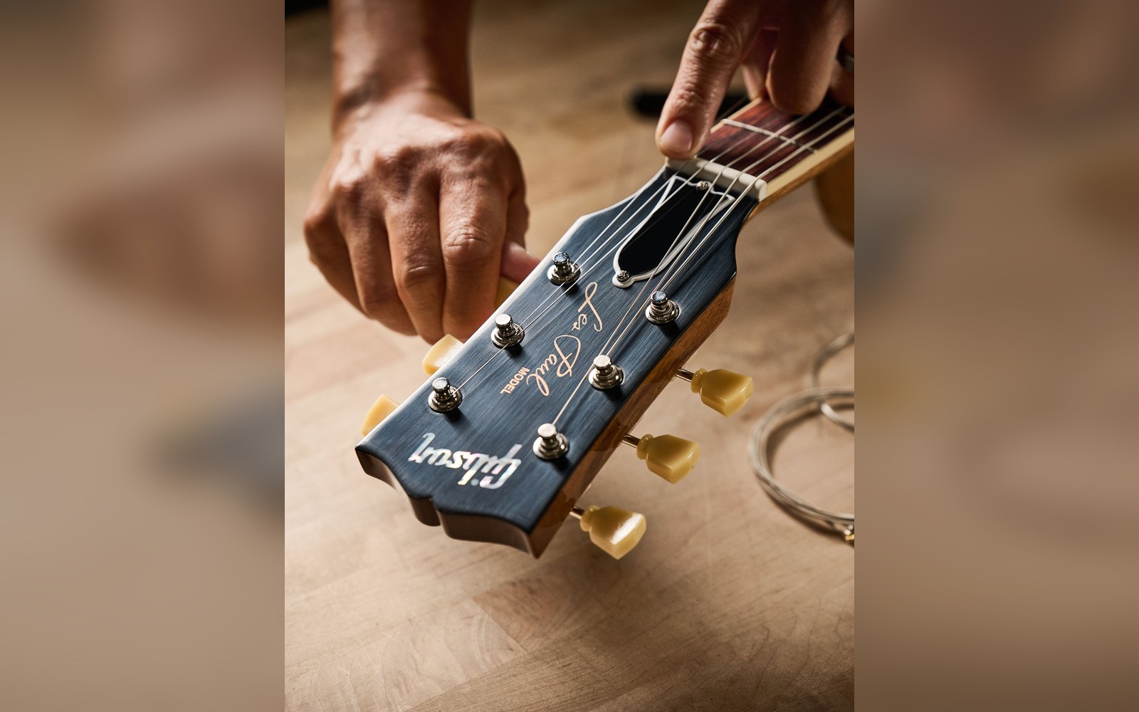 Hands adjusting tuning pegs on a Gibson Les Paul guitar headstock