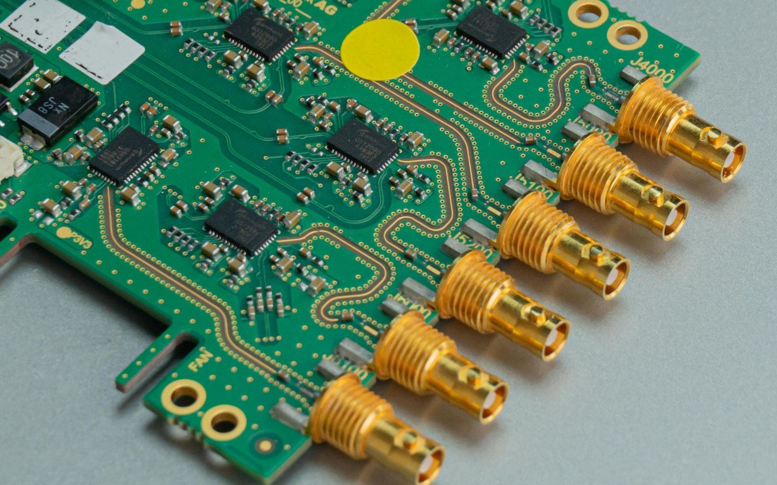 Green circuit board with gold SMA connectors and surface-mount chips soldered in place