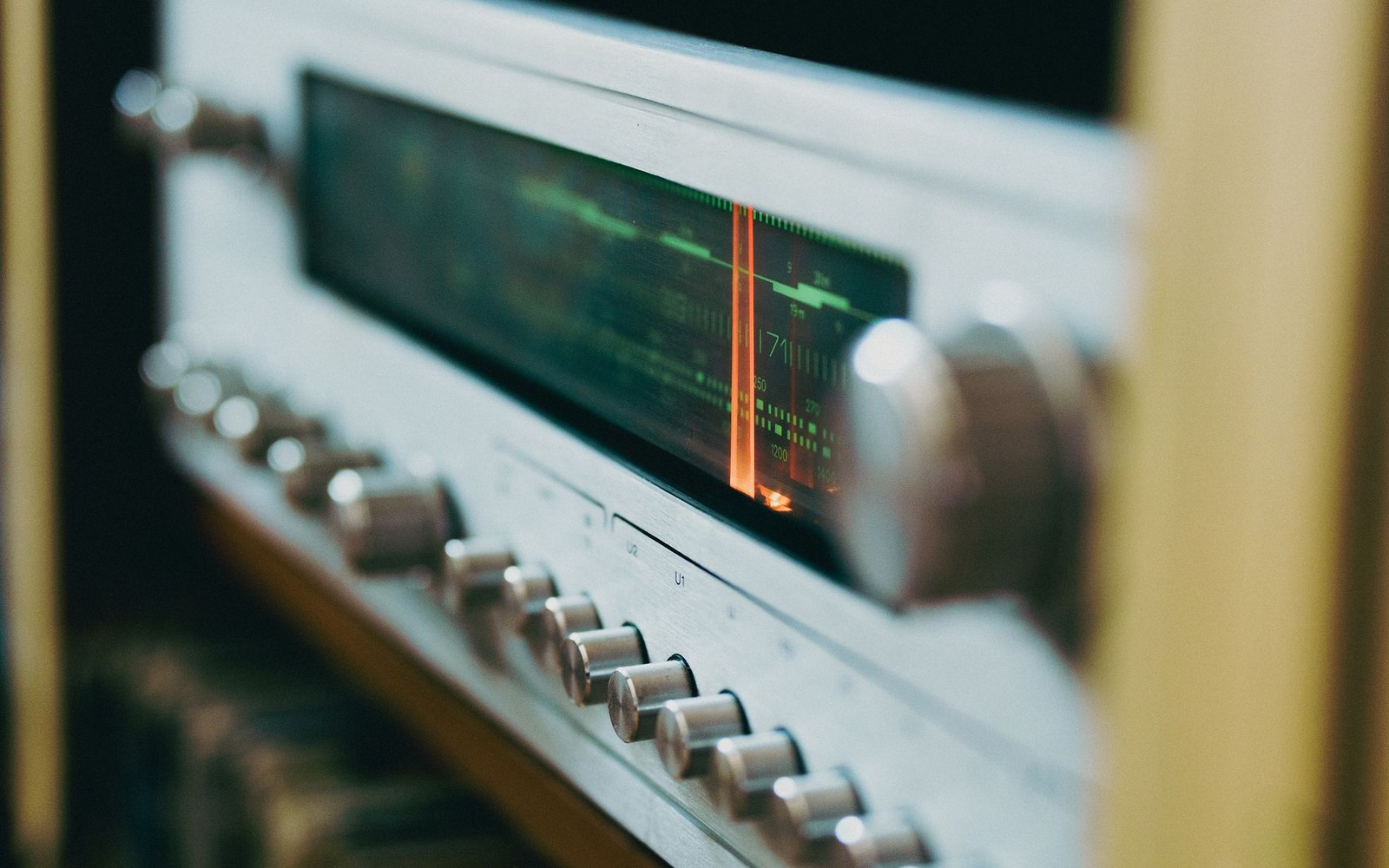 Close-up of a vintage tube amplifier's illuminated dial and control knobs